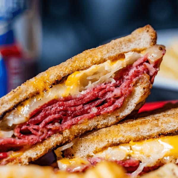 Close-up of a grilled Reuben sandwich with corned beef, sauerkraut, and melted cheese on rye bread.