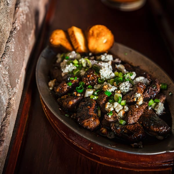 Village Idiot Pub's steak bites with blue cheese crumbles, scallions, and toasted bread.