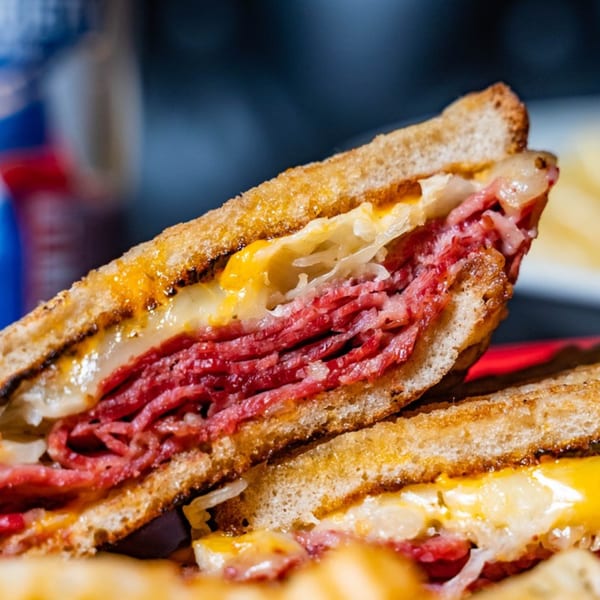 Close-up of a grilled Reuben sandwich with corned beef, sauerkraut, and melted cheese.