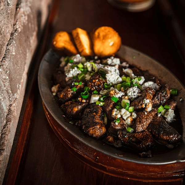 Village Idiot Pub's steak bites with crumbled cheese, green onions, and toasted bread.
